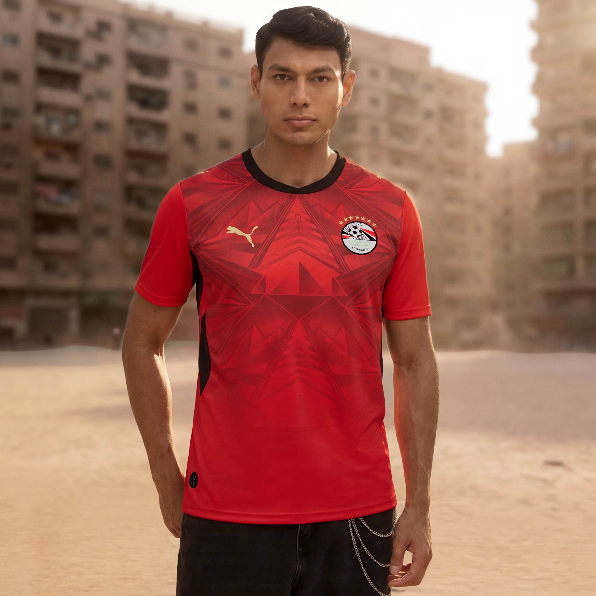 Camisa vermelha com padrão de diamantes inspirado em símbolos egípcios como a Esfinge e arsenic  pirâmides, com colarinho e punhos brancos