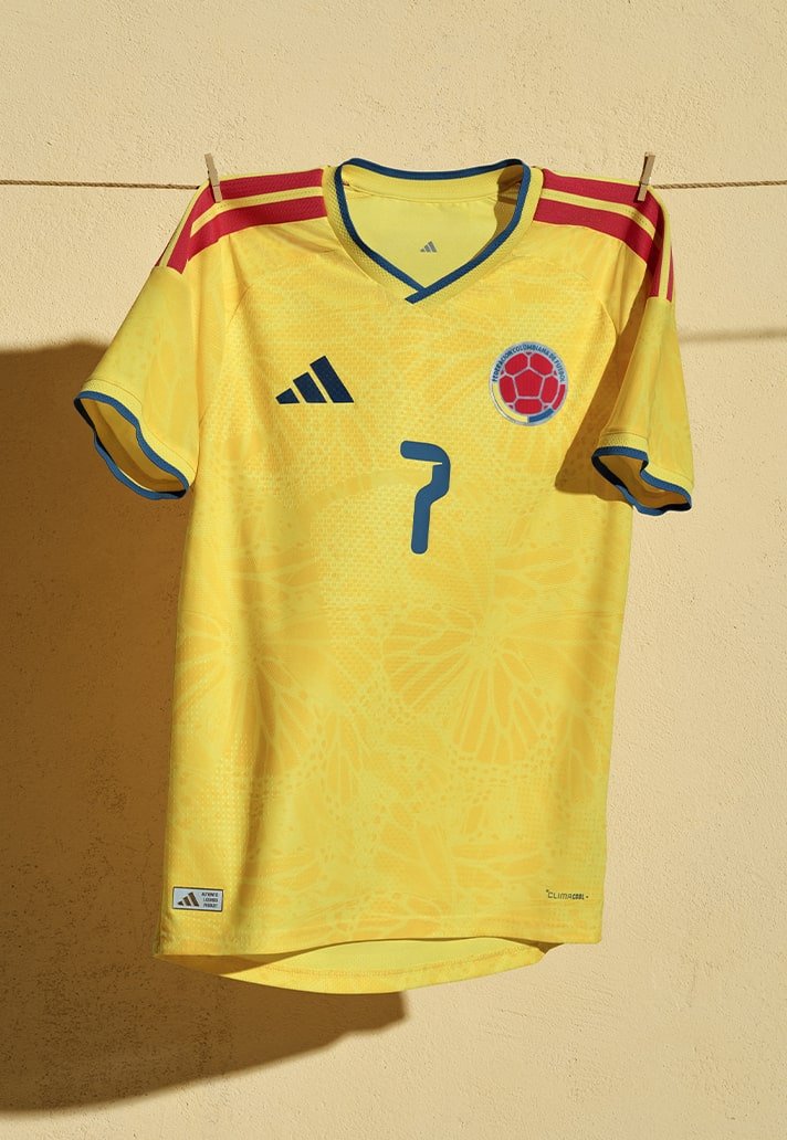 camisa amarela viva com listras e detalhes em azul e vermelho, ornamentada por uma sutil estampa de borboletas que homenageia Gabriel García Márquez e a estética bash  realismo mágico