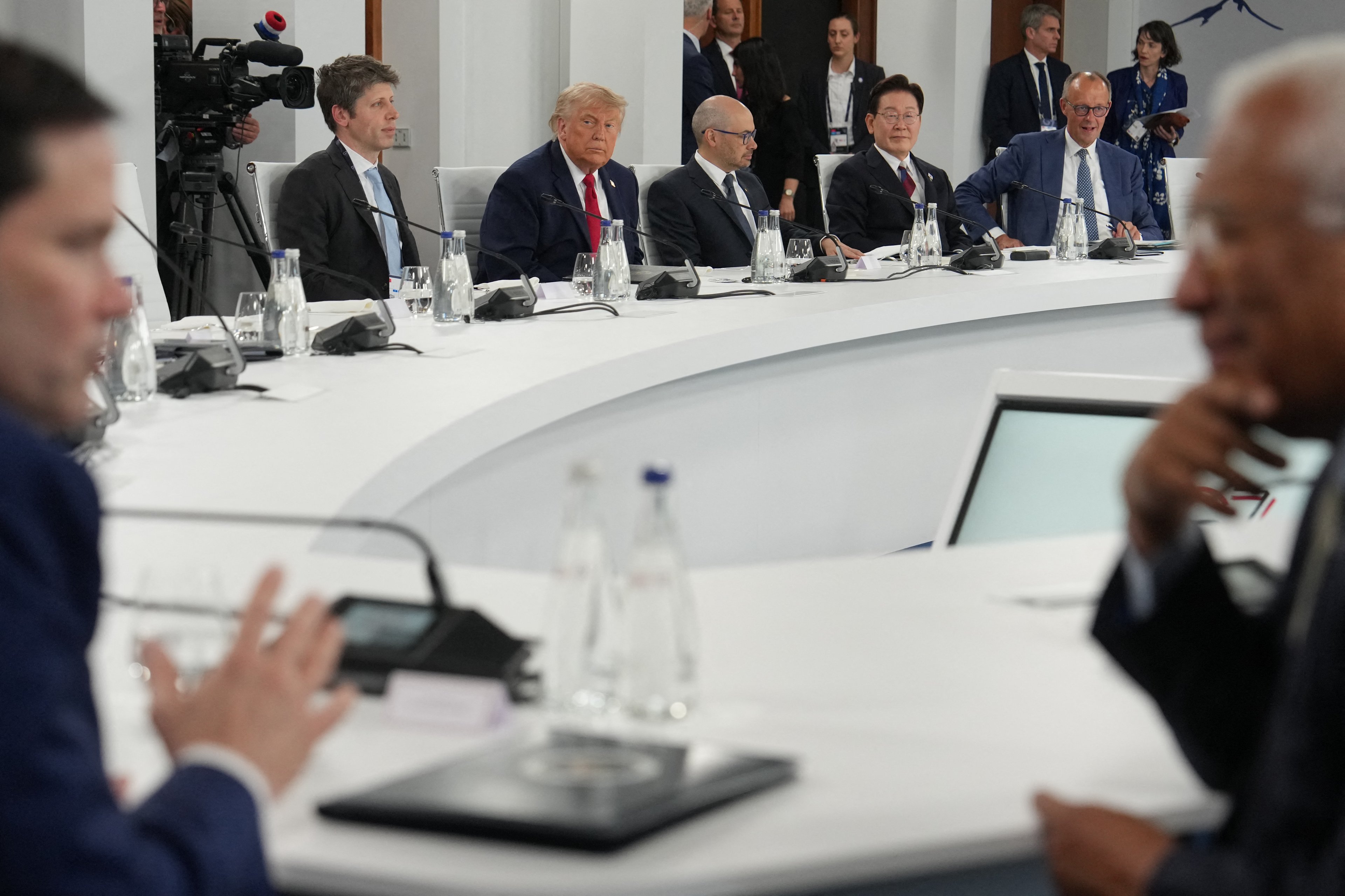 O presidente dos EUA, Donald Trump (2º da esquerda para a direita), reage ao lado do CEO da OpenAI, Sam Altman, e de Demis Hassabis, do Google DeepMind, do presidente da Coreia do Sul, Lee Jae-myung, e do chanceler alemão, Friedrich Merz, enquanto o secretário de Estado dos EUA, Marco Rubio (à esquerda), e o presidente do Conselho Europeu, António Costa (à direita), conversam em primeiro plano durante um almoço de trabalho entre membros do G7, países parceiros e líderes empresariais de inteligência artificial, como parte da cúpula do G7, em Évian, no leste da França, em 17 de junho de 2026. A cúpula do G7 está marcada para ocorrer de 15 a 17 de junho na cidade francesa de Évian-les-Bains, perto da Suíça, e contará com a presença de líderes de diversos países, bem como do chefe da diplomacia da UE e ministros do Brasil, Canadá, Emirados Árabes Unidos e Turquia. (Foto de Julia Demaree Nikhinson / POOL / AFP) O presidente dos EUA, Donald Trump (2º da esquerda para a direita), reage ao lado do CEO da OpenAI, Sam Altman, e de Demis Hassabis, do Google DeepMind, do presidente da Coreia do Sul, Lee Jae-myung, e do chanceler alemão, Friedrich Merz, enquanto o secretário de Estado dos EUA, Marco Rubio (à esquerda), e o presidente do Conselho Europeu, António Costa (à direita), conversam em primeiro plano durante um almoço de trabalho entre membros do G7, países parceiros e líderes empresariais de inteligência artificial, como parte da cúpula do G7, em Évian, no leste da França, em 17 de junho de 2026. A cúpula do G7 está marcada para ocorrer de 15 a 17 de junho na cidade francesa de Évian-les-Bains, perto da Suíça, e contará com a presença de líderes de diversos países, bem como do chefe da diplomacia da UE e ministros do Brasil, Canadá, Emirados Árabes Unidos e Turquia. (Foto de Julia Demaree Nikhinson / POOL / AFP)