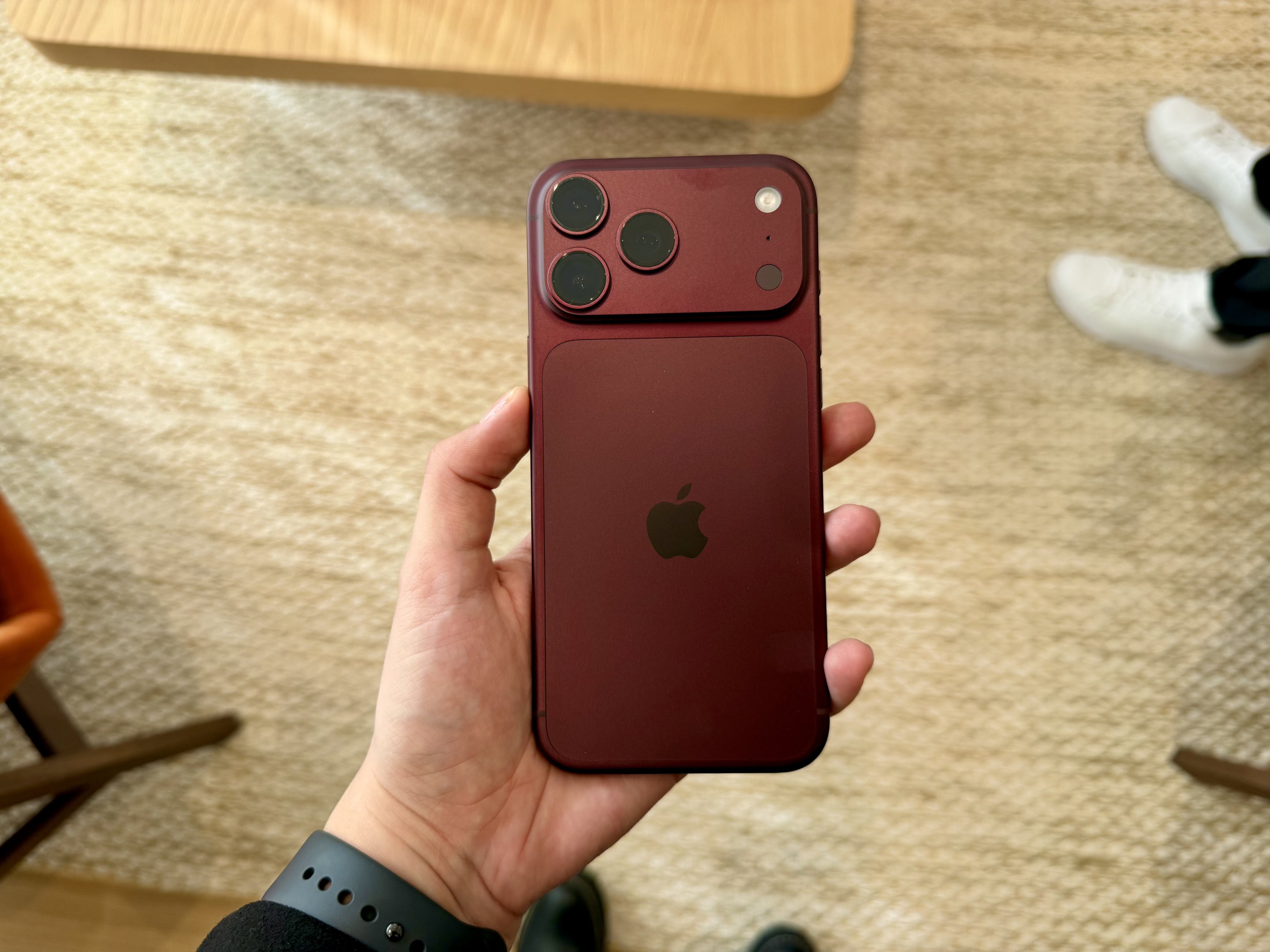 Mão segurando um iPhone 18 Pro na cor vermelha, destacando o módulo de câmeras traseiras.
