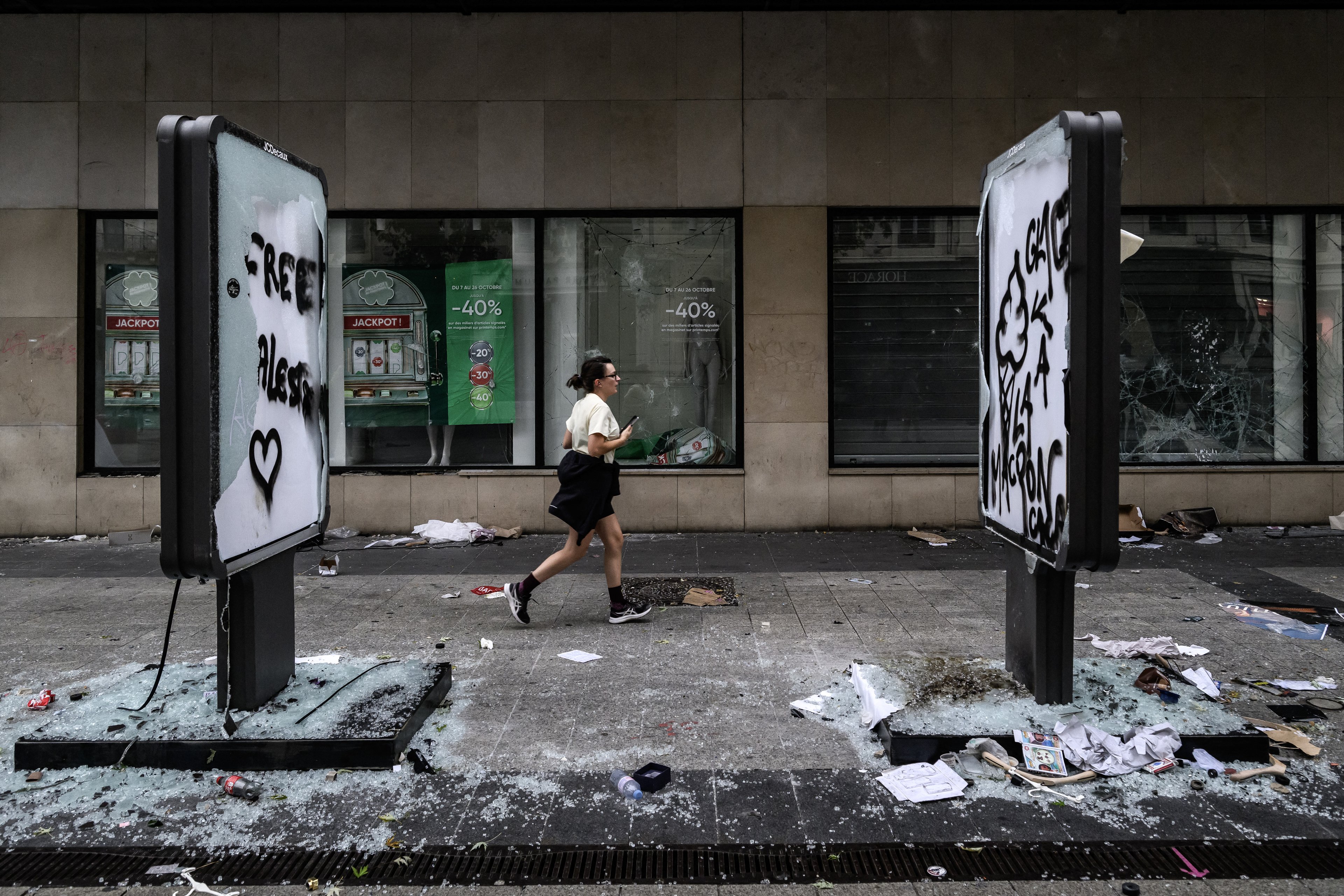 Um pedestre passa por danos e vitrines quebradas de uma loja, um dia após distúrbios e saques ocorridos durante um protesto nacional contra o 
