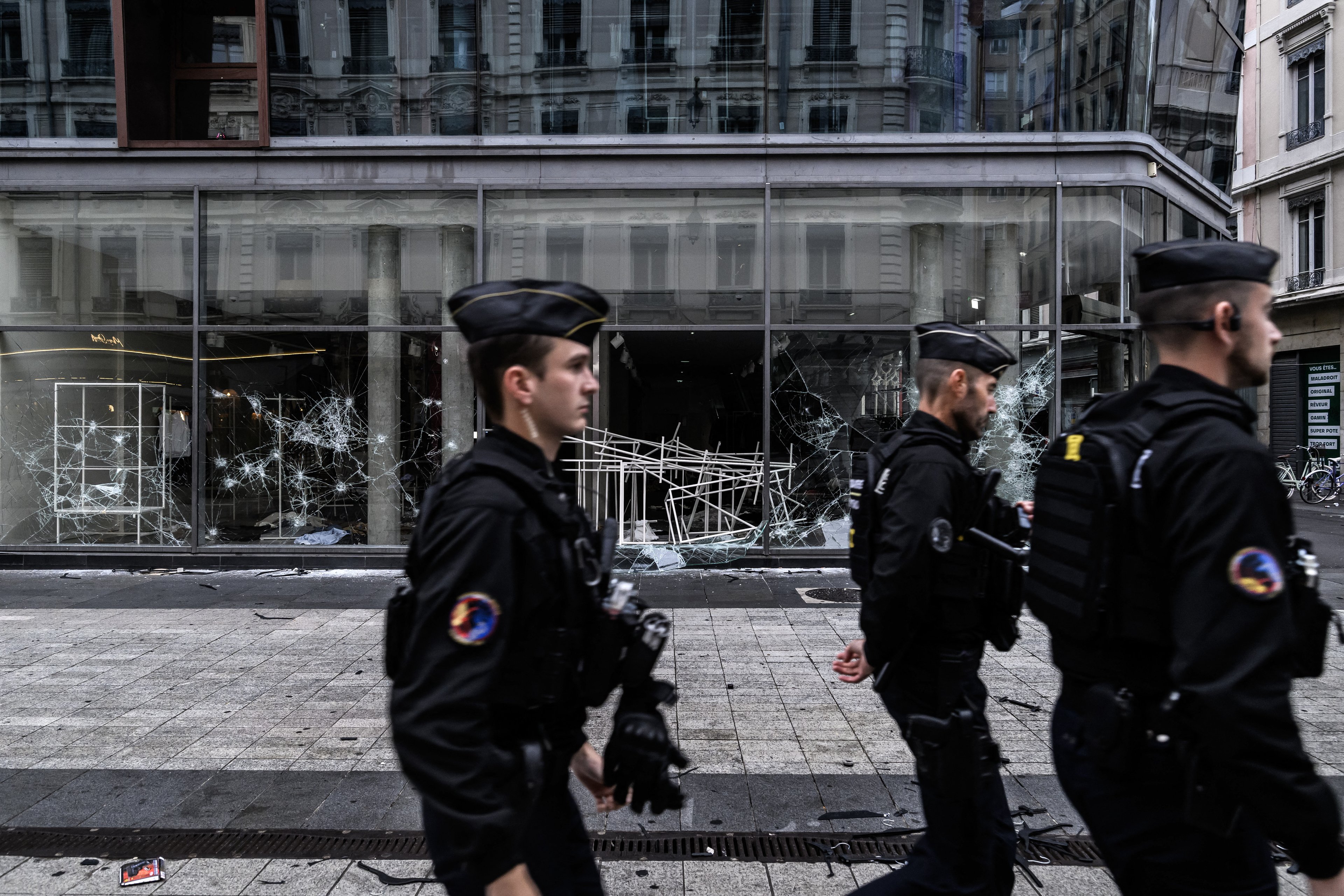 Policiais franceses (gendarmes) patrulham diante da vitrine quebrada de uma loja, um dia após distúrbios e saques ocorridos durante um protesto nacional contra o 